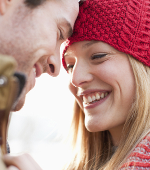 A couple who has had cosmetic dental procedures smiles at one another.